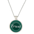 A silver chain necklace with a round pendant featuring a dark green background and the word 'Trust' in white script, set against a plain white background - Lilylin Designs