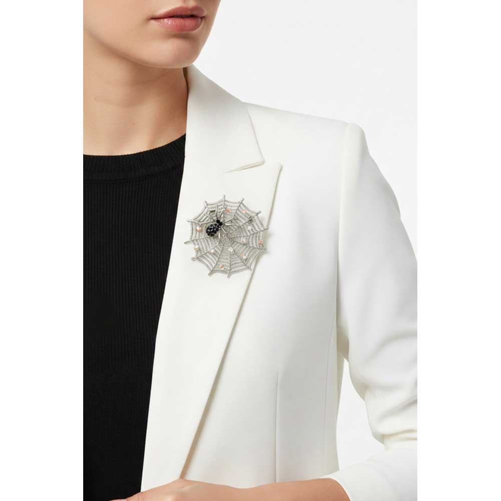 Model wearing Black crystal spider in web brooch pin on a white jacket with a black top - Lilylin Designs