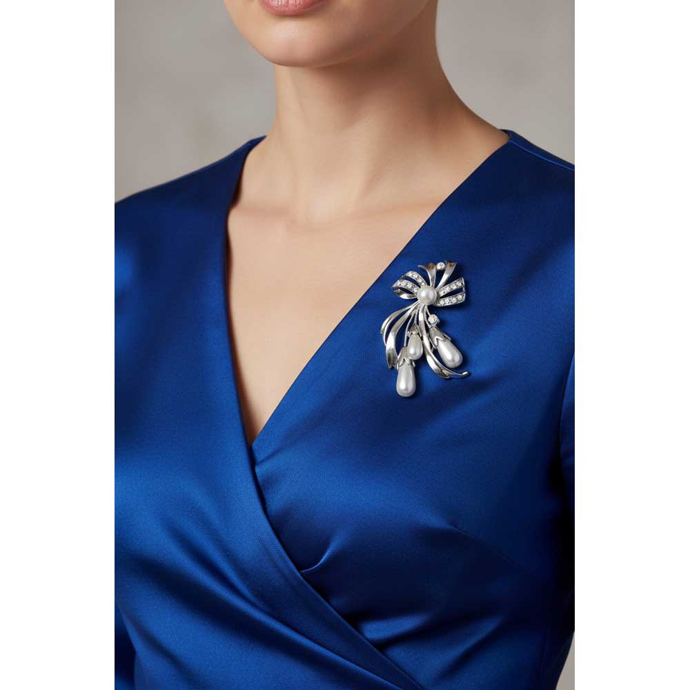 Model wearing Crystal bow with light gray pearls brooch pin on a bright blue dress - Lilylin Designs