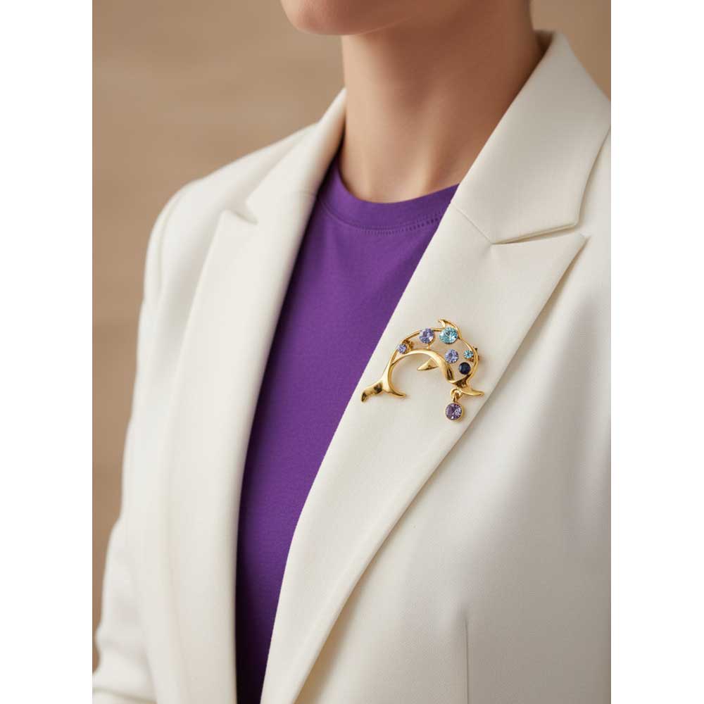 Model wearing Gold and blue crystal dolphin brooch pin on a white jacket with a purple top - Lilylin Designs