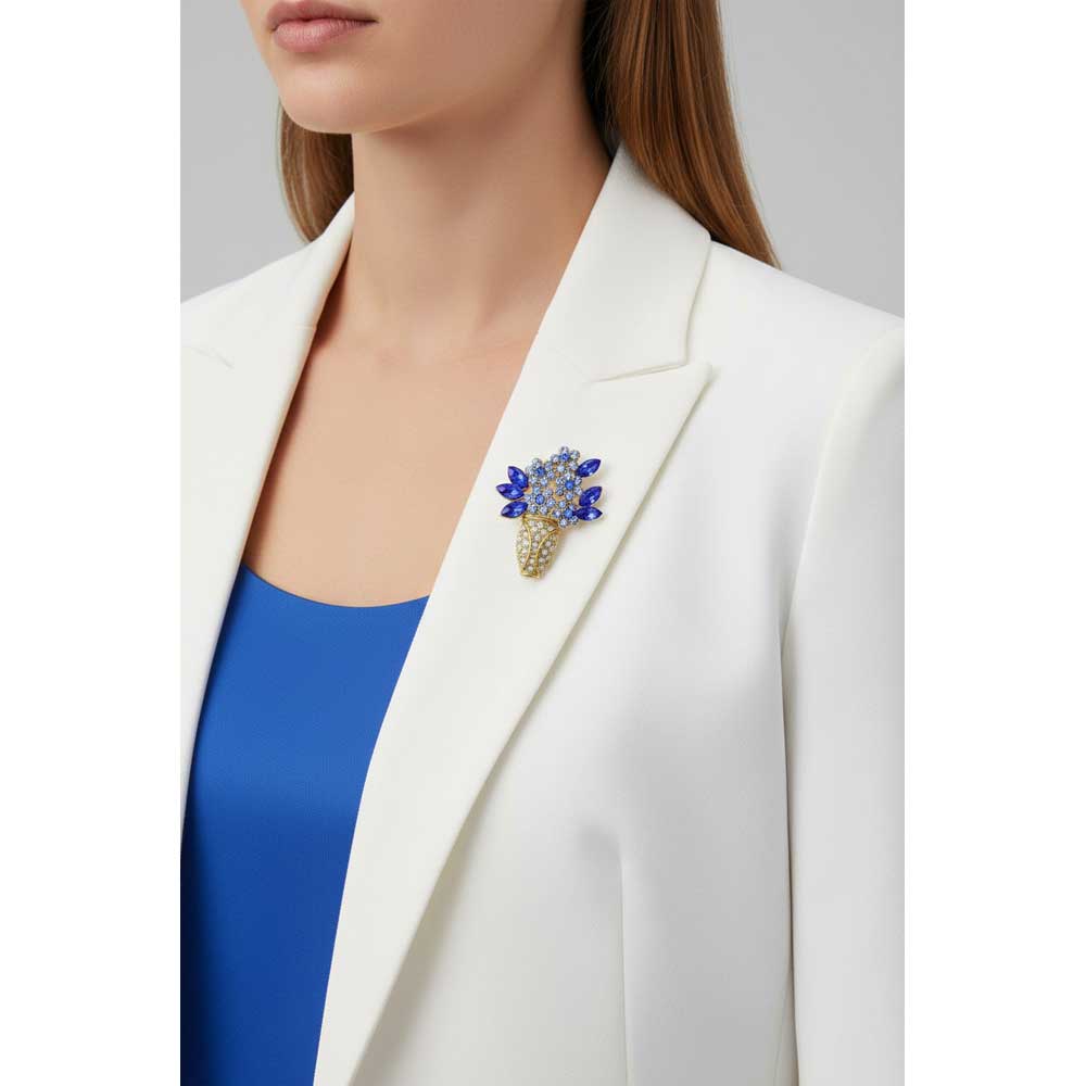 Model wearing Gold vase with blue flowers brooch pin on a white jacket with a blue top - Lilylin Designs