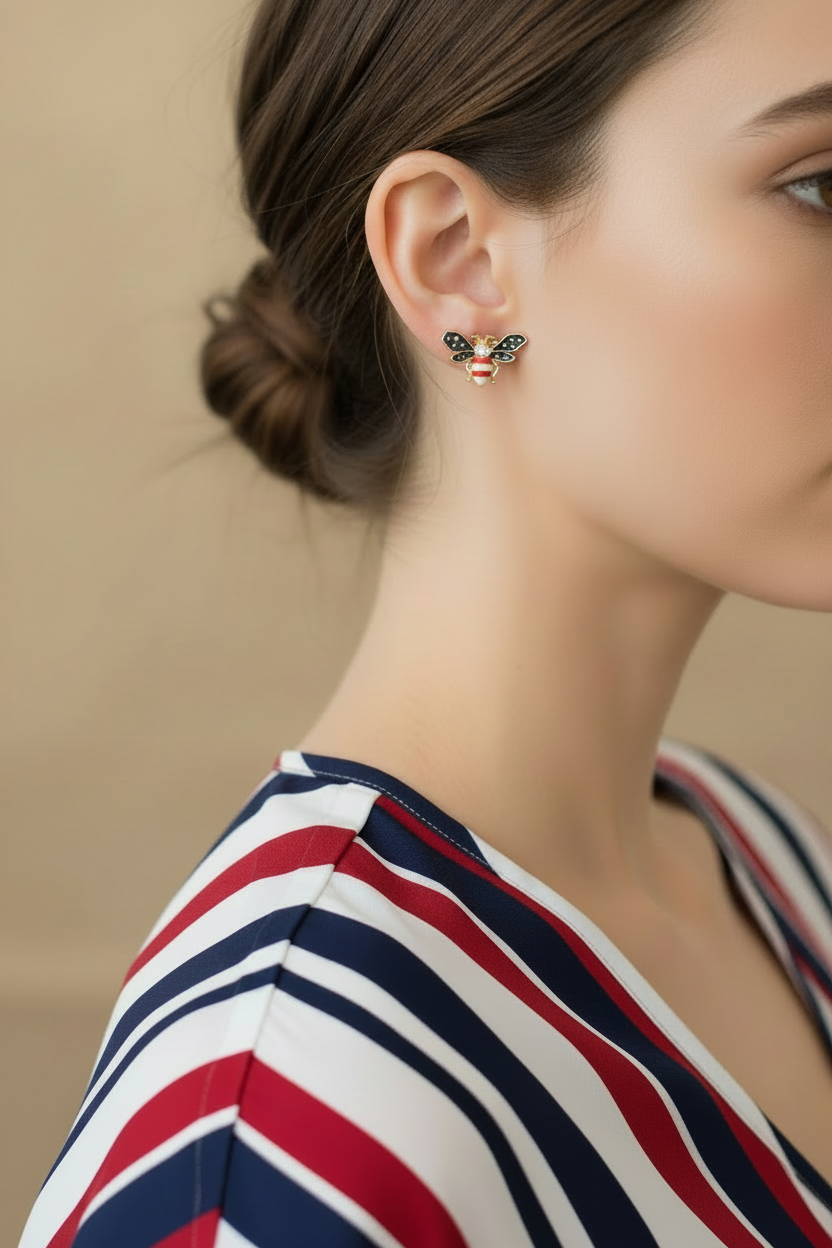 A close-up of a woman wearing a small bee-shaped stud earring with  red, white and blue details - Lilylin Designs