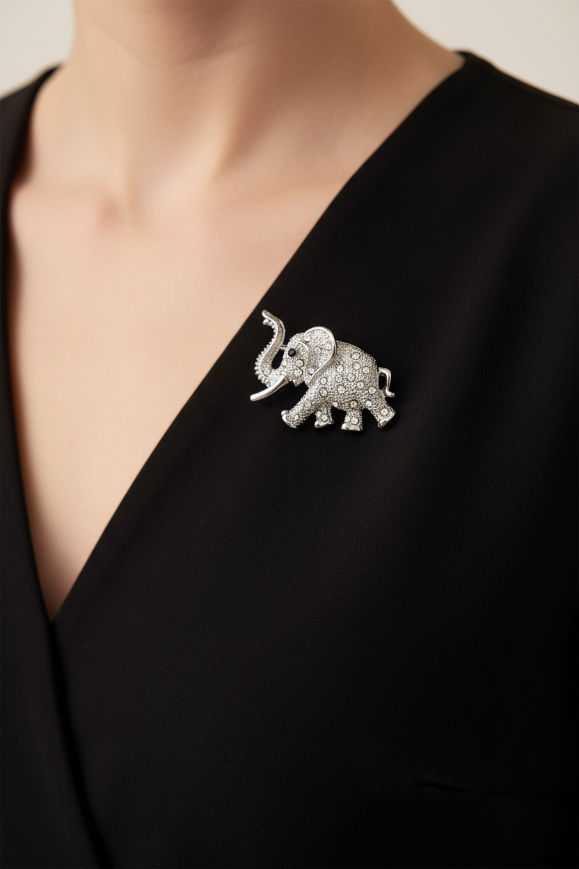 A silver elephant brooch embellished with clear crystals, pinned to the black V-neck blouse of a model. Lilylin Designs