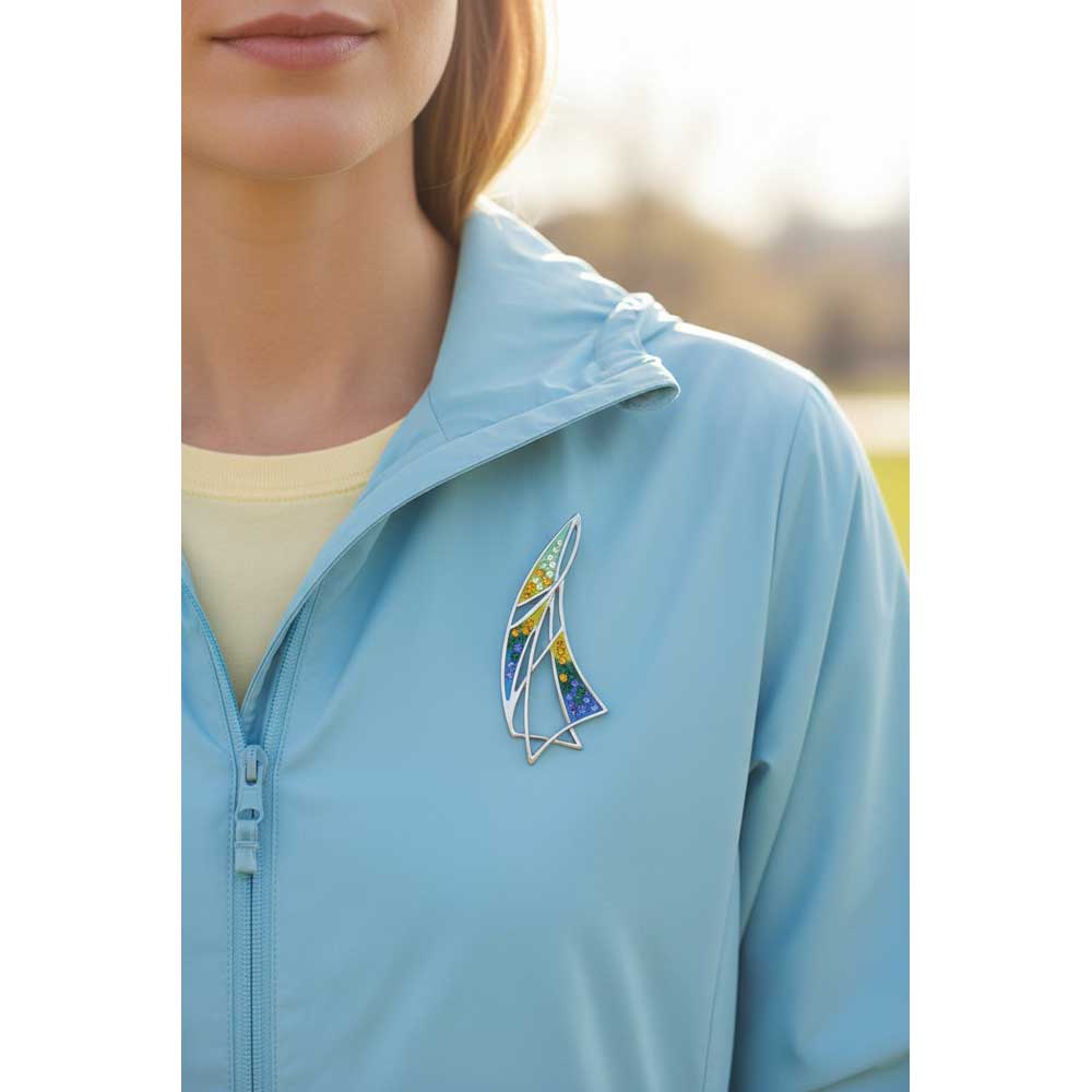 Model wearing colorful enamel sailboat pin on a light blue jacket - Lilylin Designs