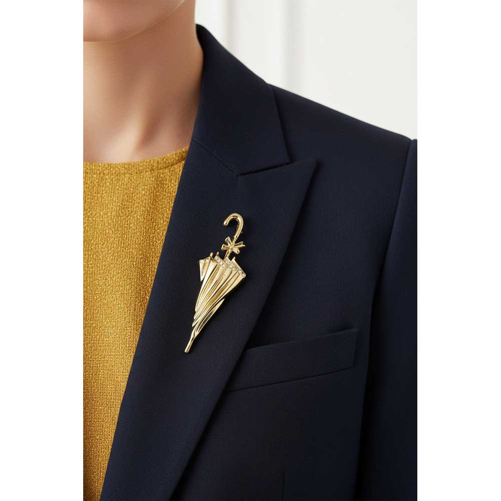 A gold umbrella-shaped brooch pinned to the lapel of a navy blazer over a mustard yellow knit top. Lilylin Designs