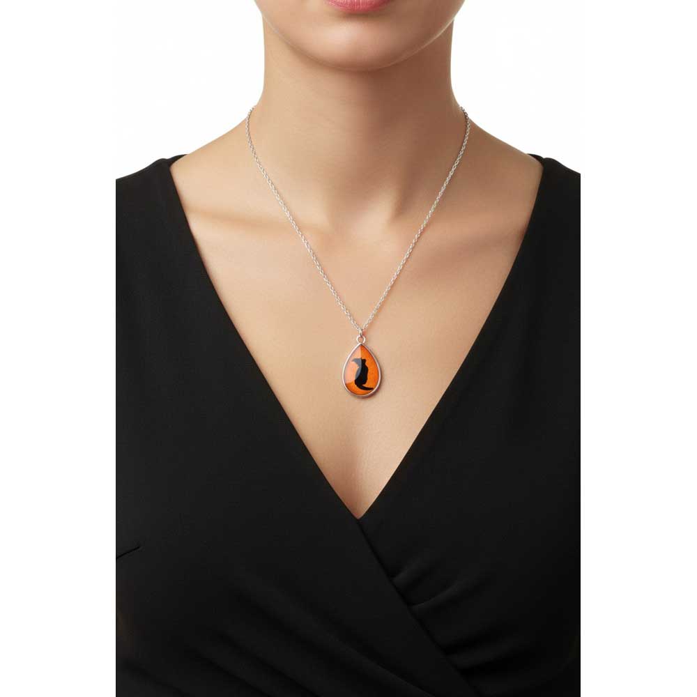 Model wearing Lilylin Designs handcrafted orange teardrop with black witchy cat necklace with a black dress