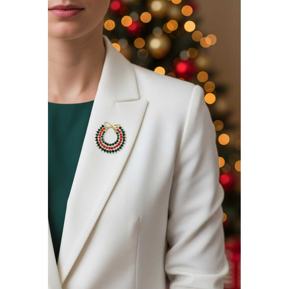 Model wearing red and green crystal wreath with gold bow on a white jacket with a holiday background - Lilylin Designs