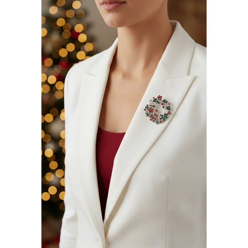 Model wearing red and green daisies Christmas brooch pin on a white jacket in front of a blurred Christmas tree - Lilylin Designs