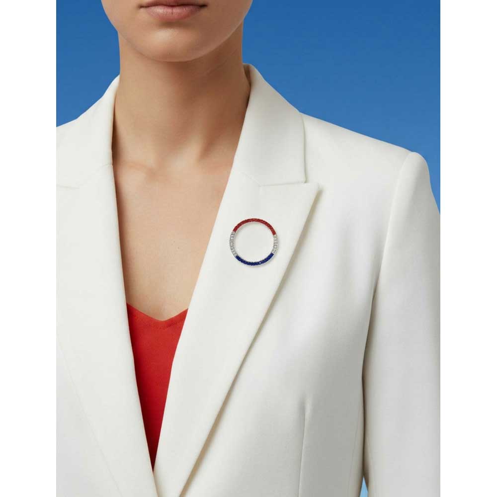 Model wearing red white and blue crystal infinity circle pin on a white jacket with blue skies in the background - Lilylin Designs