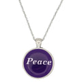A silver chain necklace with a round pendant featuring a deep purple background and the word 'Peace' written in white script, set against a plain white background - Lilylin Designs