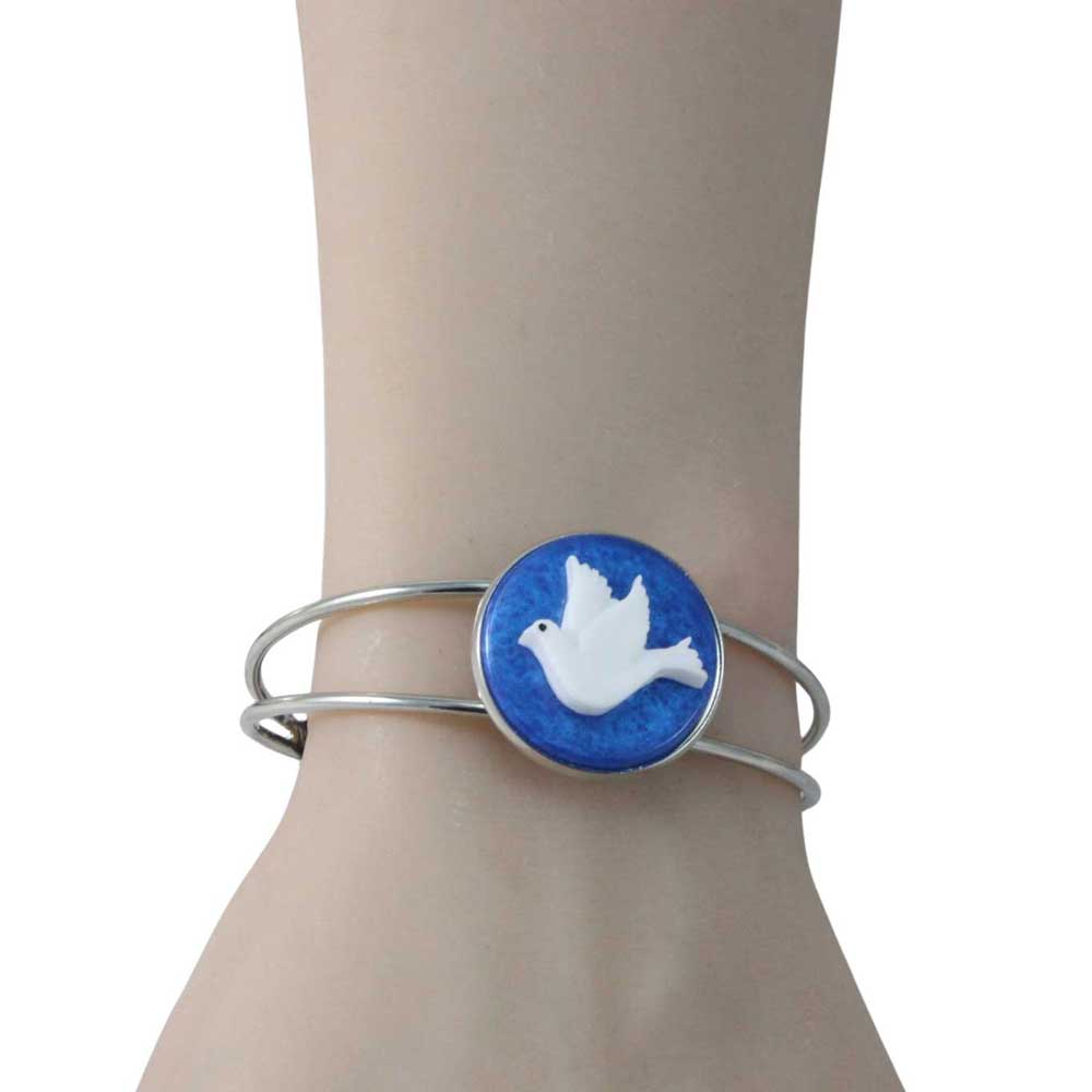 Silver bracelet with a blue and white dove design on a wrist.