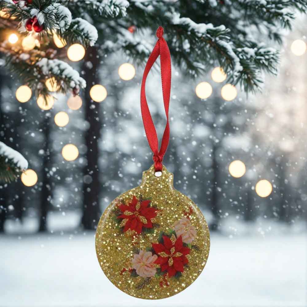 Decorative Christmas ornament with poinsettias on a gold glittery background, hanging from a tree in a snowy scene | Lilylin Designs