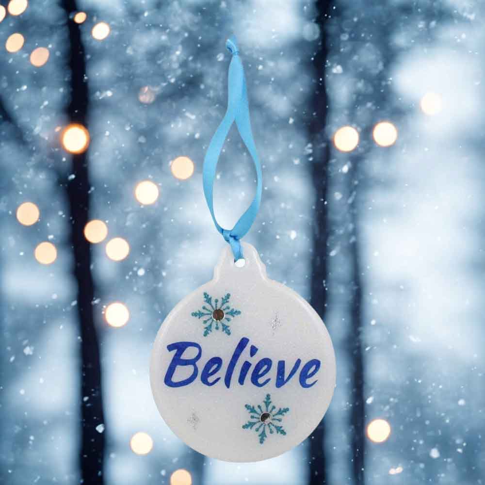 Decorative ornament with 'Believe' text against a snowy forest background | Lilylin Designs