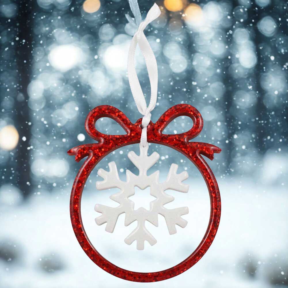 Decorative ornament with red frame and white snowflake design against a snowy background | Lilylin Designs
