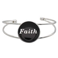 A silver-toned metal cuff bracelet featuring a round black disc with the word 'Faith' printed in white script, shown on a plain white background – Lilylin Designs