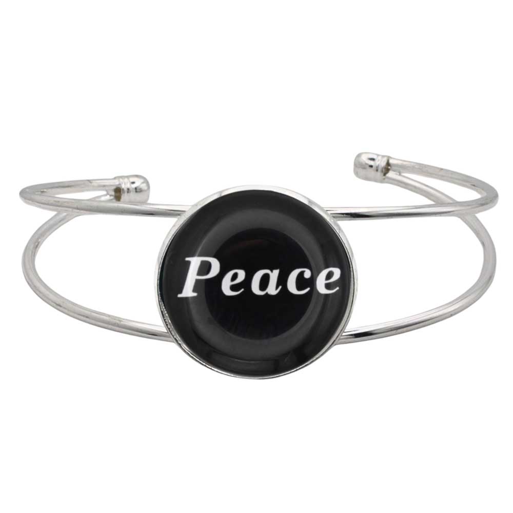 A silver-toned metal cuff bracelet featuring a round black disc with the word 'Peace' printed in white script, shown on a plain white background – Lilylin Designs