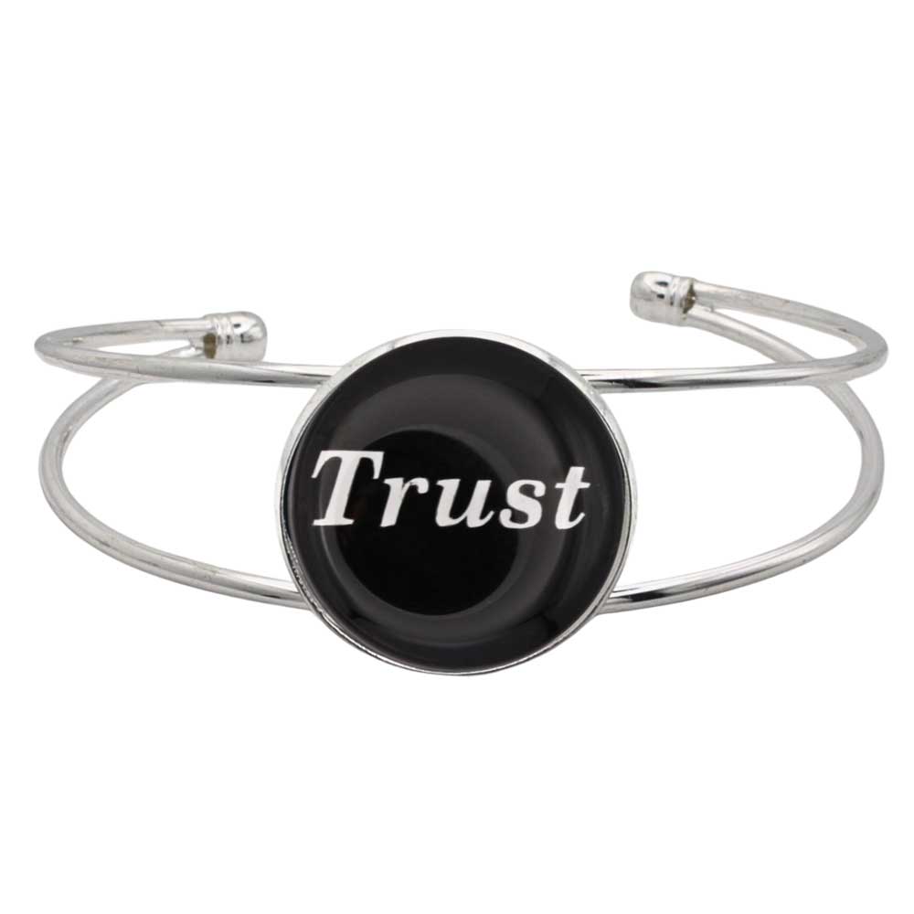 A silver-toned metal cuff bracelet featuring a round black disc with the word 'Trust' printed in white script, shown on a plain white background – Lilylin Designs