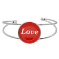 A silver-toned metal cuff bracelet featuring a round red disc with the word 'Love' printed in white script, shown on a plain white background – Lilylin Designs