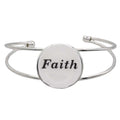 A silver-toned metal cuff bracelet featuring a round white disc with the word “Faith” printed in black script, shown on a plain white background – Lilylin Designs