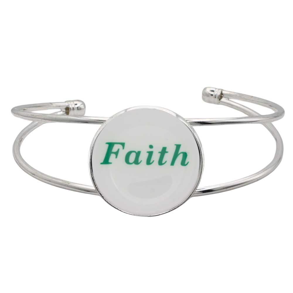 A silver-toned metal cuff bracelet featuring a round white disc with the word “Faith” printed in green script, shown on a plain white background – Lilylin Designs