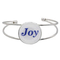 A silver-toned metal cuff bracelet featuring a round white disc with the word 'Joy' printed in blue script, shown on a plain white background – Lilylin Designs