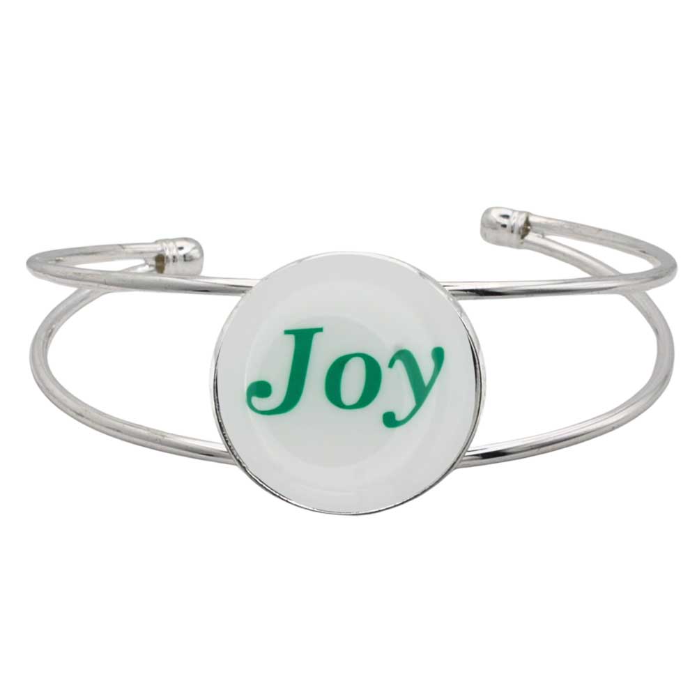 A silver-toned metal cuff bracelet featuring a round white disc with the word 'Joy' printed in green script, shown on a plain white background – Lilylin Designs