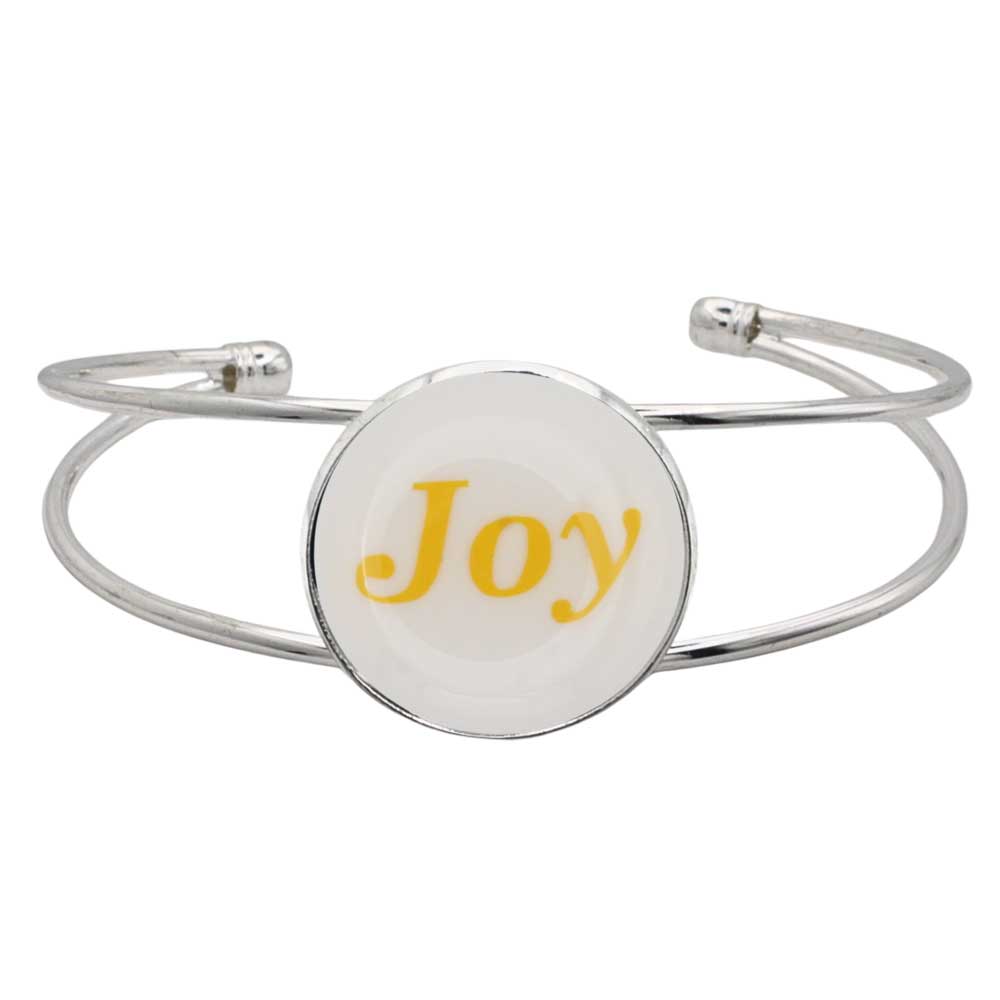 A silver-toned metal cuff bracelet featuring a round white disc with the word 'Joy' printed in yellow script, shown on a plain white background – Lilylin Designs