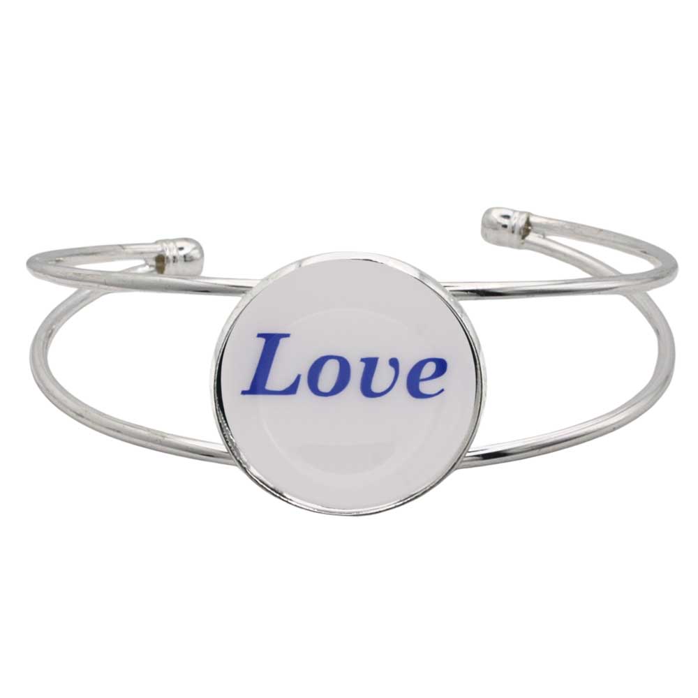 A silver-toned metal cuff bracelet featuring a round white disc with the word “Love” printed in blue script, shown on a plain white background – Lilylin Designs