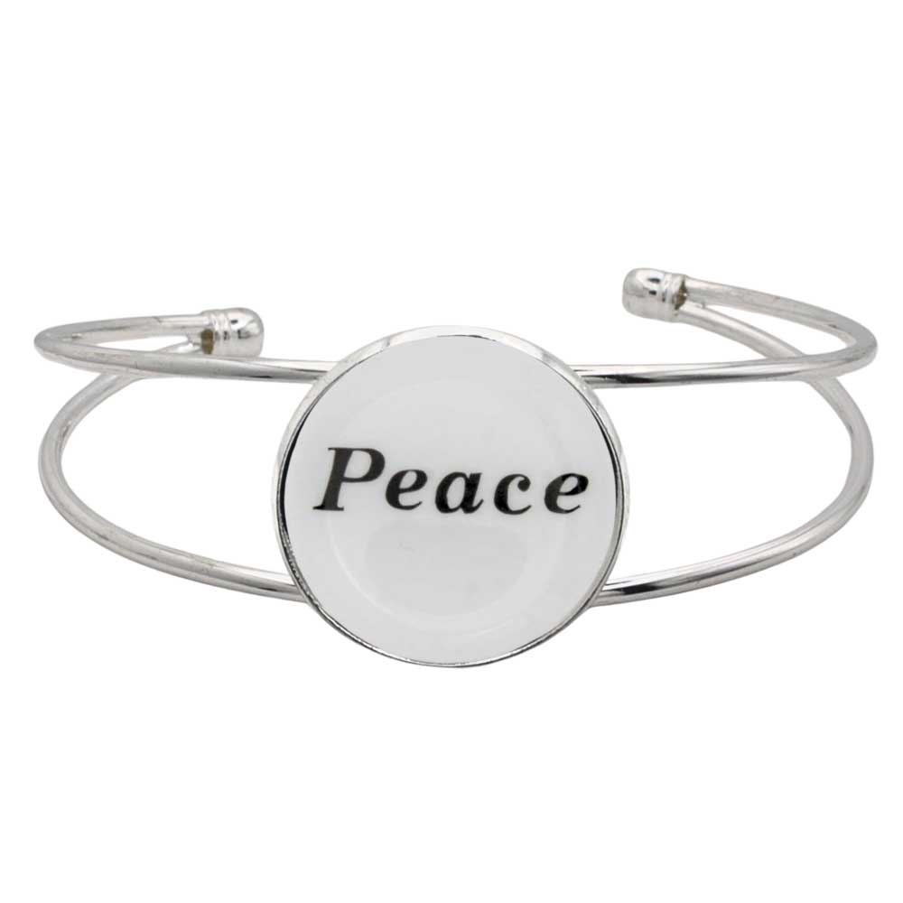 A silver-toned metal cuff bracelet featuring a round white disc with the word “Peace” printed in black script, shown on a plain white background – Lilylin Designs
