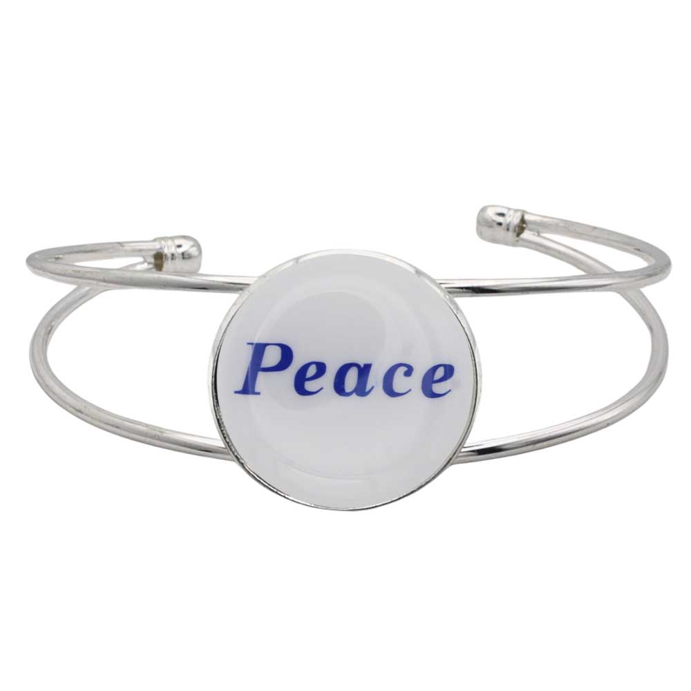 A silver-toned metal cuff bracelet featuring a round white disc with the word “Peace” printed in blue script, shown on a plain white background – Lilylin Designs