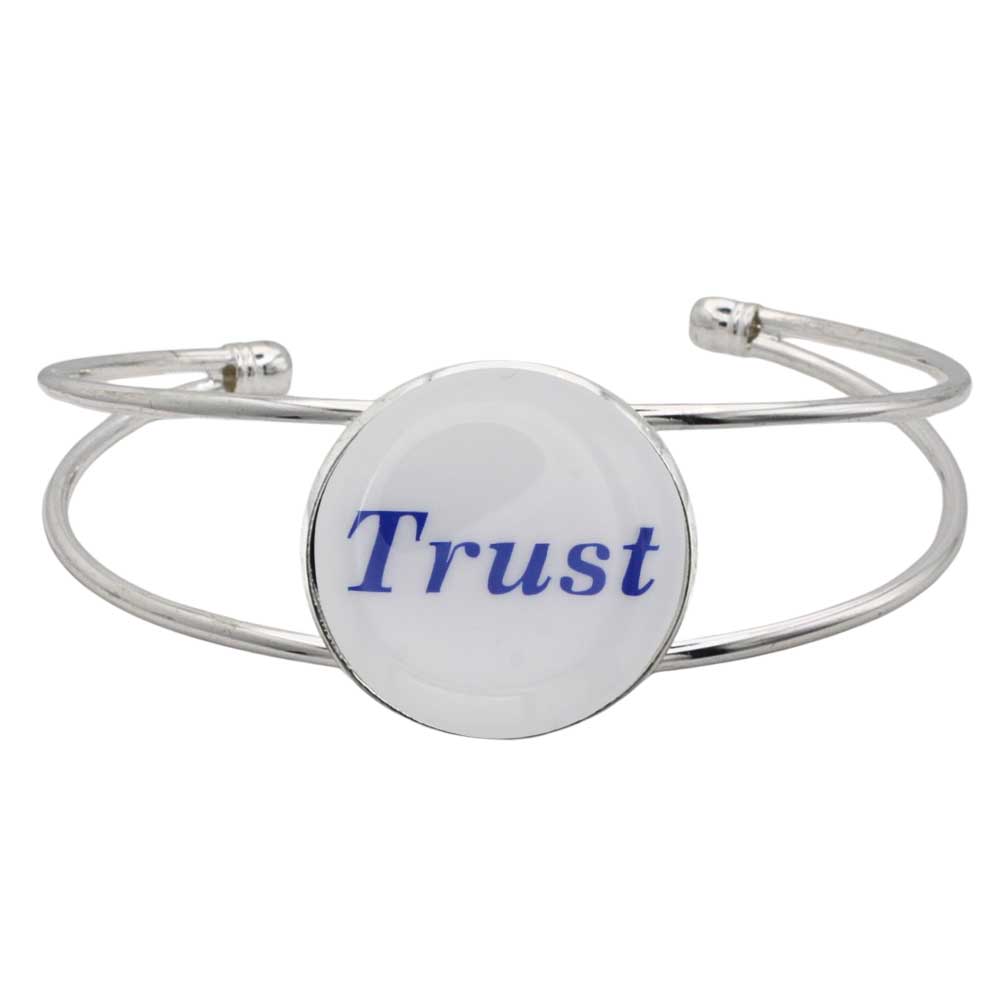 A silver-toned metal cuff bracelet featuring a round white disc with the word "Trust" printed in blue script, shown on a plain white background – Lilylin Designs