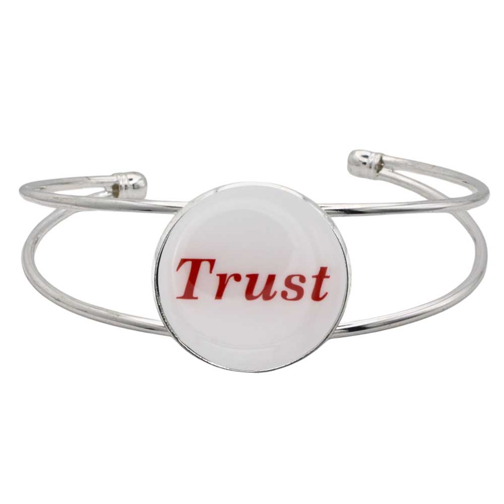 A silver-toned metal cuff bracelet featuring a round white disc with the word "Trust" printed in red script, shown on a plain white background – Lilylin Designs