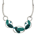 A silver-toned statement necklace featuring organic-shaped green and teal stone elements, accented by two small round blue stones, shown on a plain white background. Lilylin Designs