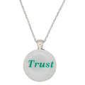 A silver chain necklace with a round pendant featuring the word 'Trust' in green text on a white background, shown against a plain white backdrop - Lilylin Designs