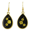 Black teardrop earrings with gold floral designs on a white background